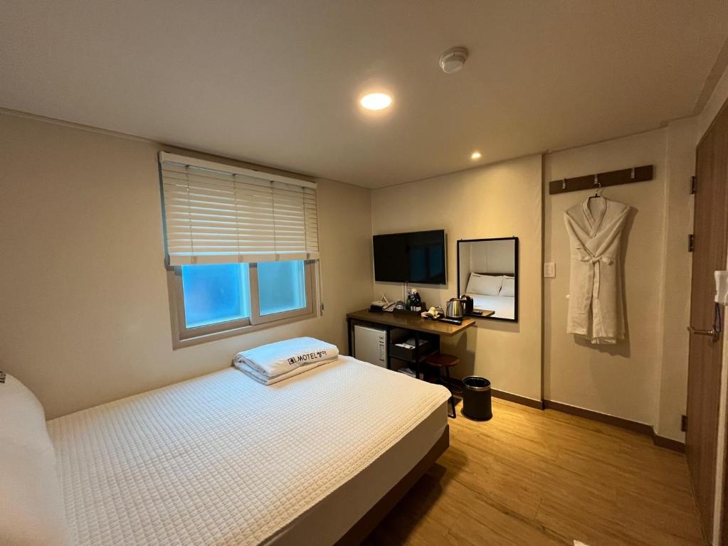 釜山Ssangma Motel的卧室配有一张床,墙上挂着一连衣裙
