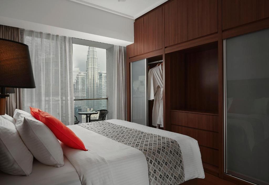 吉隆坡TRILLION SUITES by SLG的一间卧室配有一张带红色枕头的床和一扇窗户