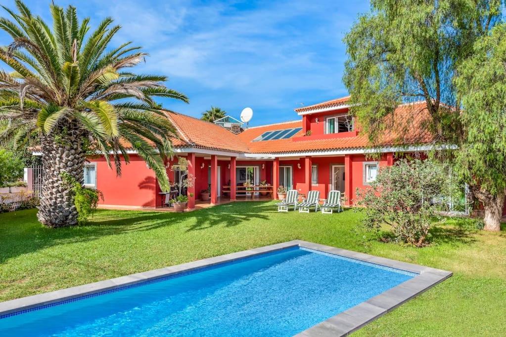 拉克鲁斯Villa Artigar, garden, swimming pool and bbq.的棕榈树和游泳池的红色房子