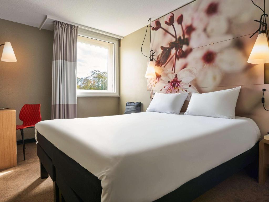 厄梅瑞维尔厄梅瑞维尔巴黎马恩河谷宜必思酒店的酒店客房设有一张白色大床,墙上挂着鲜花