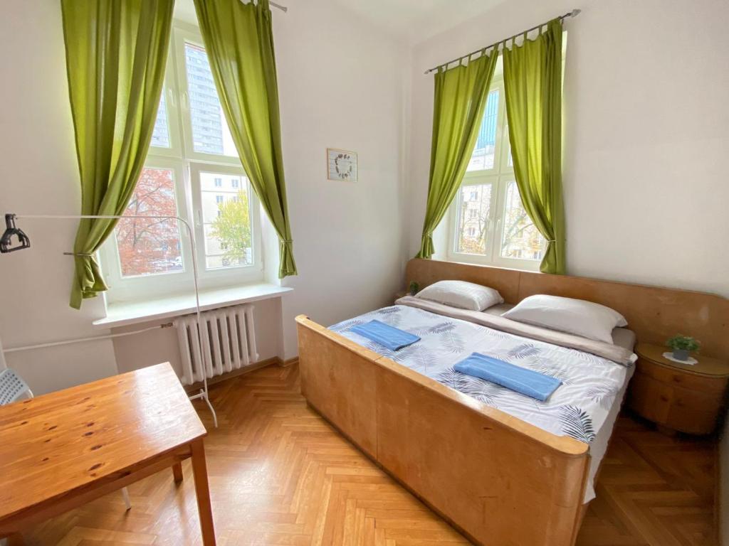 华沙Oliwka Hostel的一间卧室配有一张带绿色窗帘的床和一张桌子