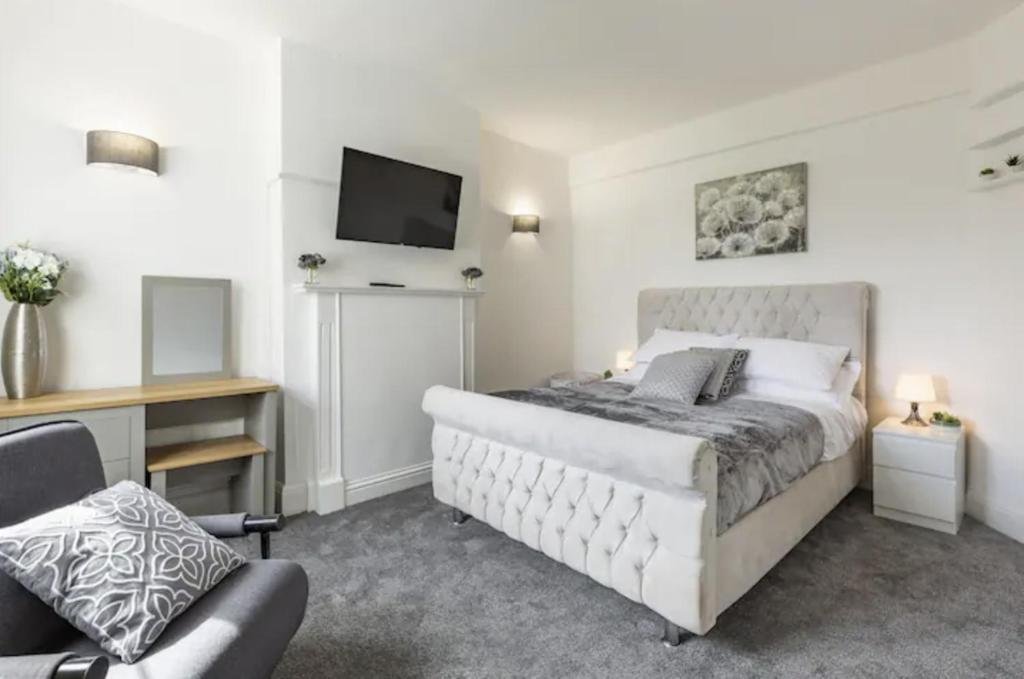 HornchurchLuxury 3-Bed Apartment Near To London With Parking的一间卧室配有一张床、一台电视和一把椅子