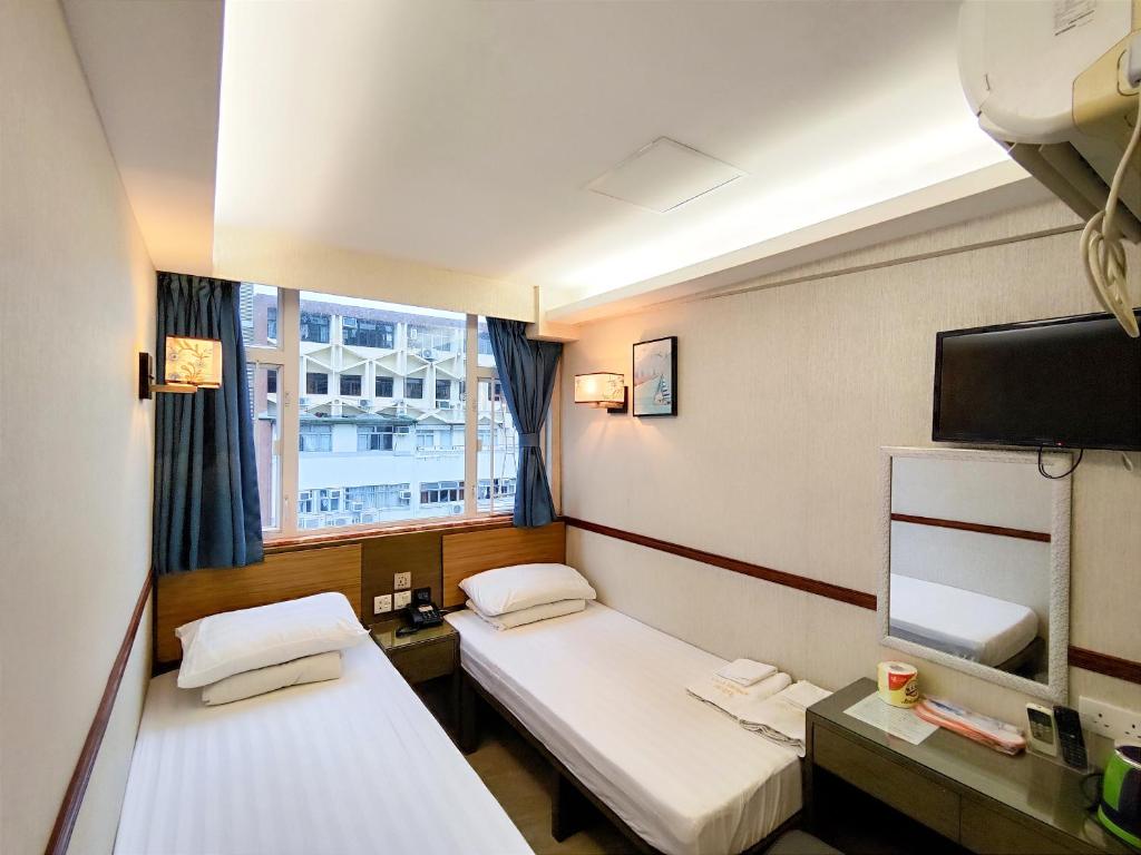 香港Celltronik Hostel 先創旅店的客房设有两张床、一台电视和一扇窗户。