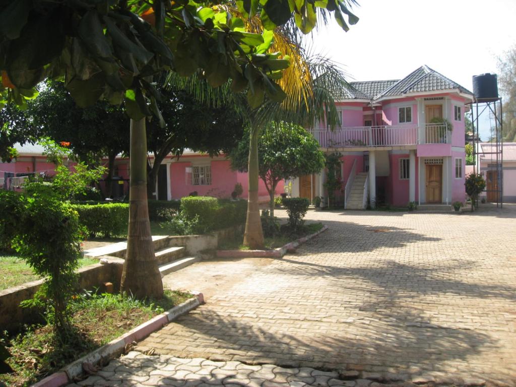 MbaleR&R Gardens Hotel的前面有树木的粉红色房子