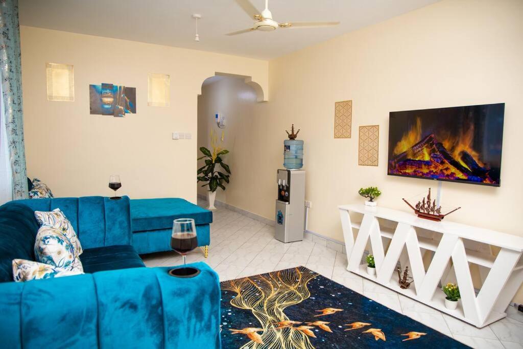 蒙巴萨Royal Haven A3 Spacious 1Br Apartment 10min drive to beach hosts upto 4 guests WiFi - Netflix, 10min drive to beach的客厅配有蓝色的沙发和电视