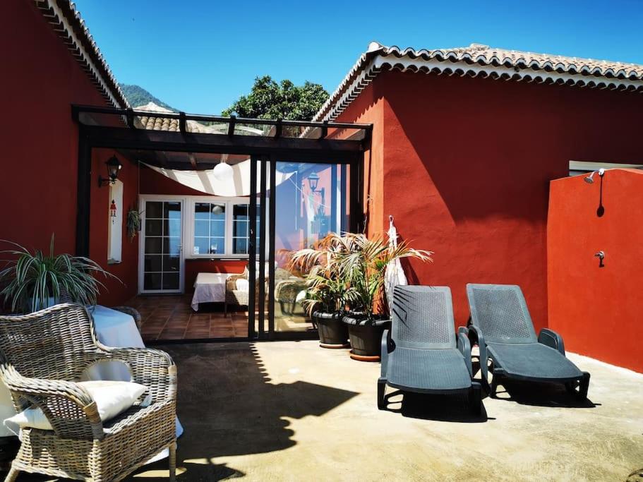 圣克鲁斯-德拉帕尔马CASA ISA, ideal para descansar.的一个带柳条椅和红色房子的庭院