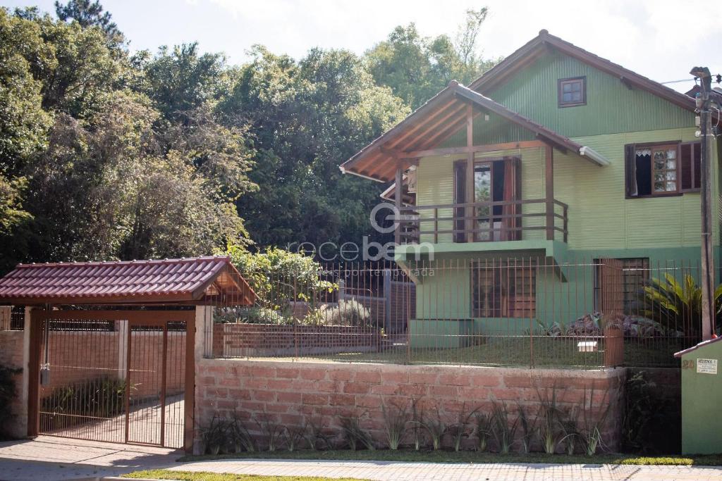新彼得罗波利斯Casa Completa - Nova Petrópolis的一座带门和栅栏的绿色房子