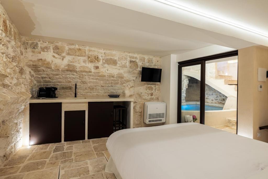 奥斯图尼Suite Le Grotte的卧室配有白色的床和石墙