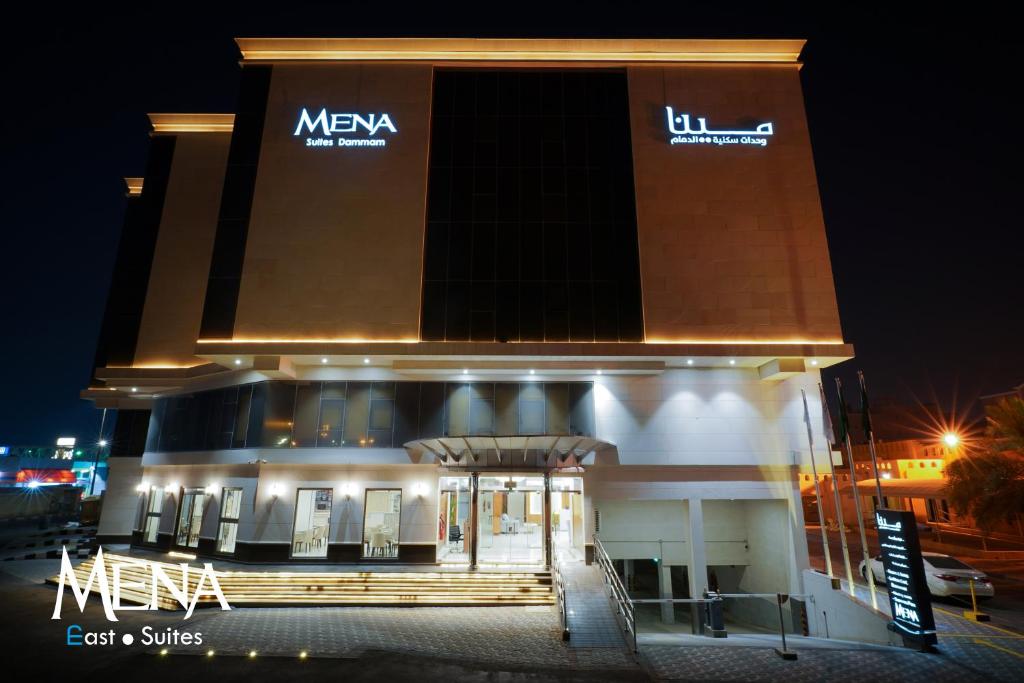 达曼Mena East Suites Dammam的一座大建筑,晚上有标志