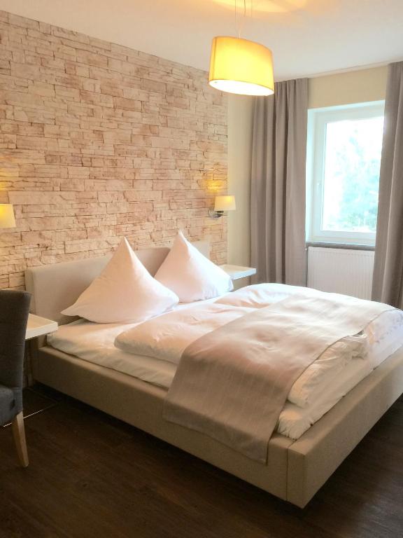 Kirkel阿喀琉斯酒店的一间卧室设有一张带砖墙的大床