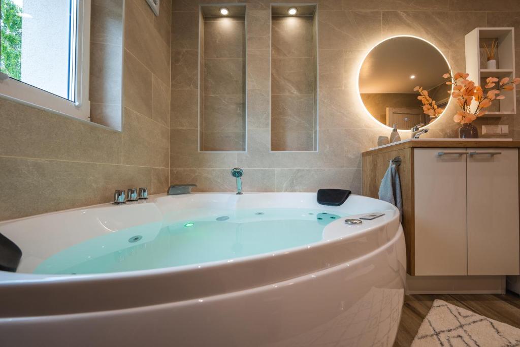 奥泰佩Otepää Holiday Apartment with Jacuzzi的一个带镜子的浴室内的白色大浴缸