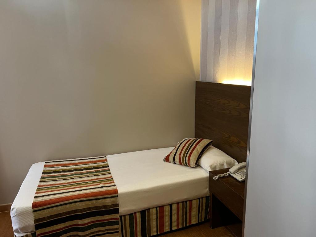 马德里劳斯考罗纳尔斯旅馆的一间小卧室,配有一张床和一部电话