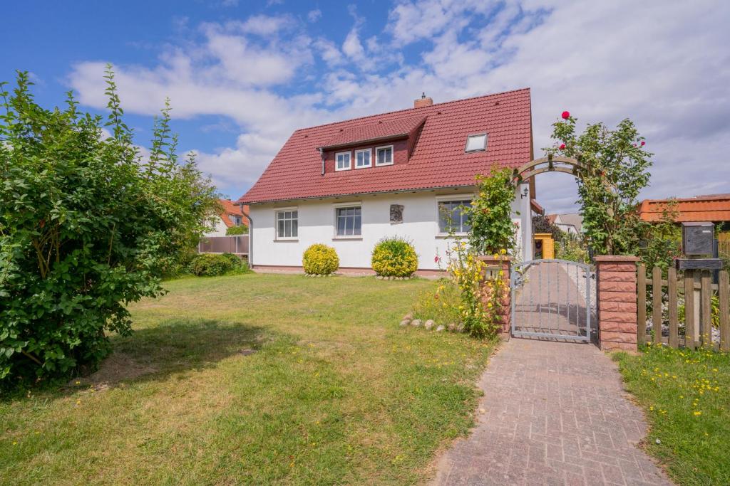 朗克维茨Ferienhaus "Seeadler" in Rankwitz am Peenestrom的白色的房子,有红色的屋顶和院子