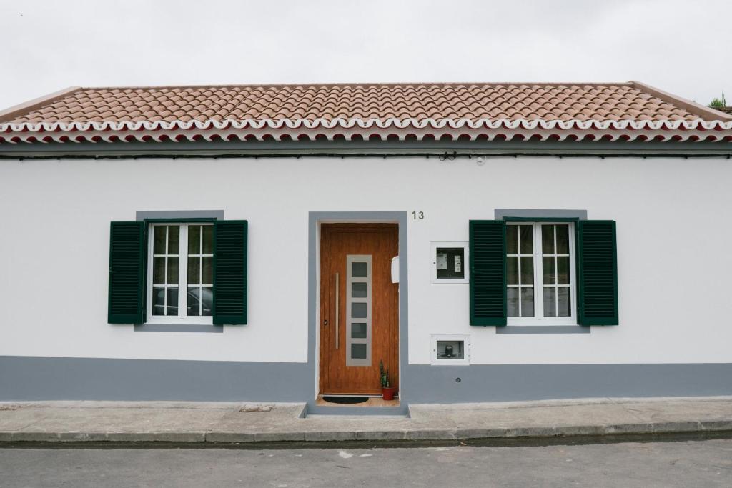 大里贝拉Village House的白色的房子,有绿色百叶窗和门