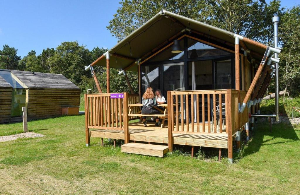 卡兰茨奥赫Safari Lodge, glamping aan zee!的坐在凉亭桌子上的女人