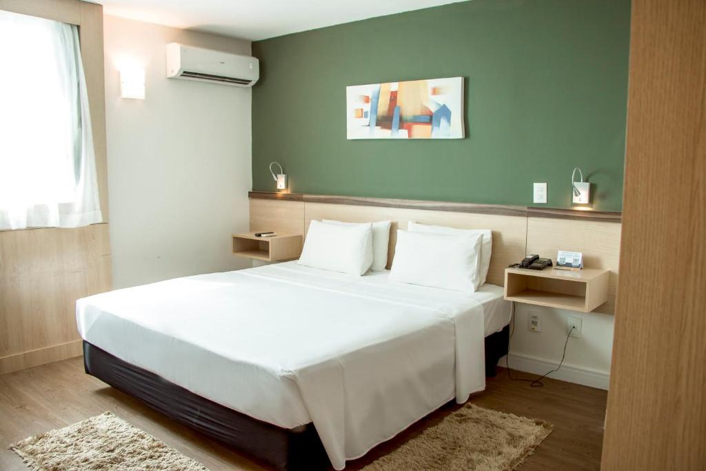 坎普斯戈伊塔卡济斯坎波斯多斯戈塔卡兹舒适酒店的卧室配有白色的床和绿色的墙壁