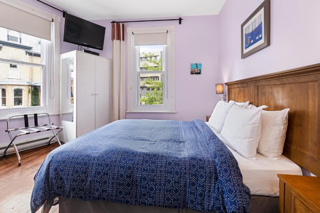 魁北克市塔林城堡酒庄酒店的一间卧室配有一张带蓝色棉被的床和窗户。