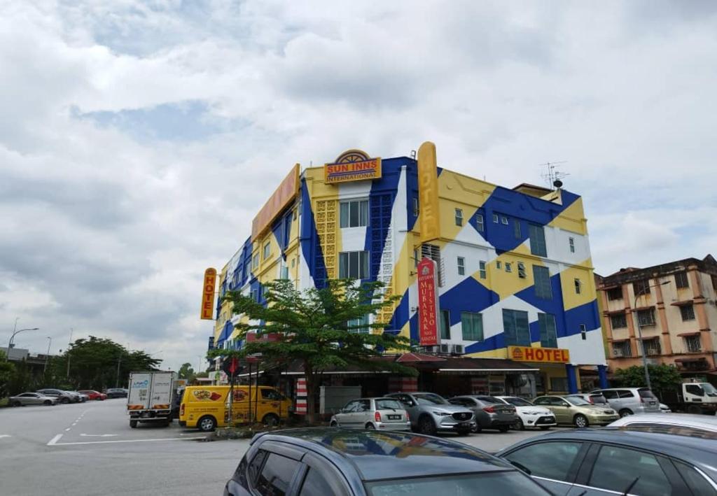 蕉赖蕉赖太阳之星酒店 - 巴拉孔的一座黄色和蓝色的建筑,停车场有车辆停放