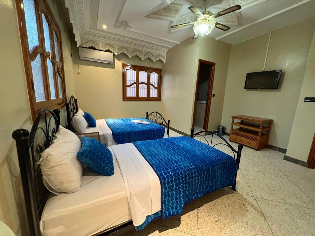 扎古拉Riad Perlamazigh的一间卧室配有两张带蓝白色床单的床