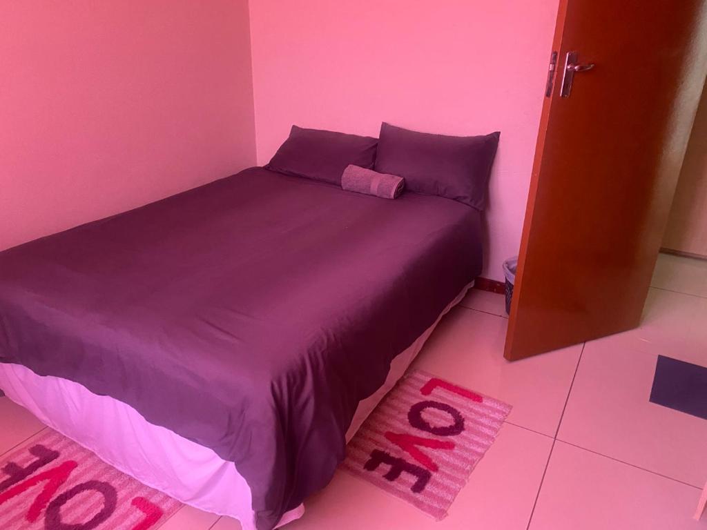 AcademiaToke homestay nr 37 omatjene street Cimbabacia的粉红色的卧室,配有一张带紫色床单的床