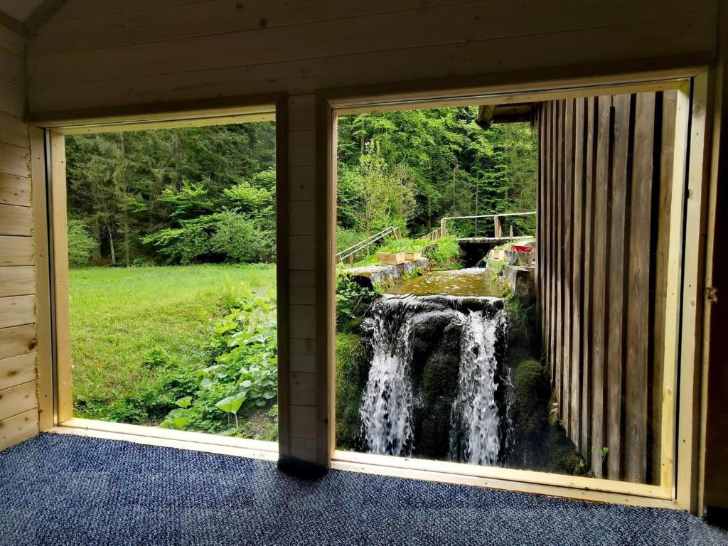 普利特维采湖Wooden house with a waterfall "Stipanov mlin"的从房子的窗户可欣赏到瀑布的景色