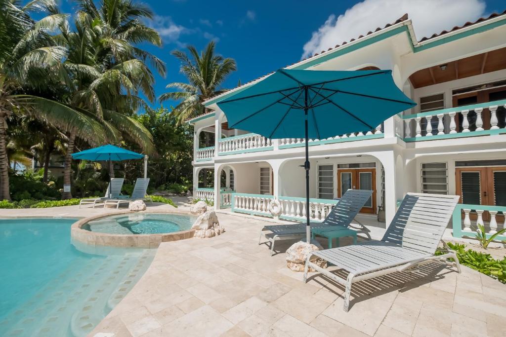圣佩德罗Coral Bay Villas的一座房子,设有游泳池、椅子和遮阳伞
