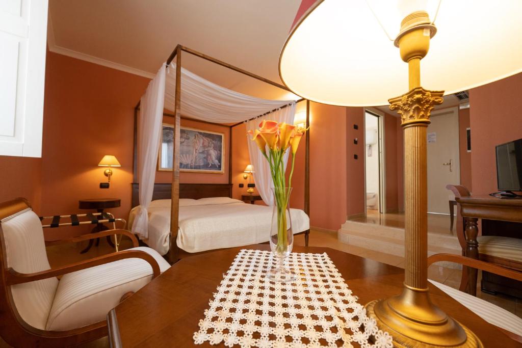 维博瓦伦蒂亚韦基亚威宝餐厅酒店的一间卧室配有一张床和一张花瓶桌子