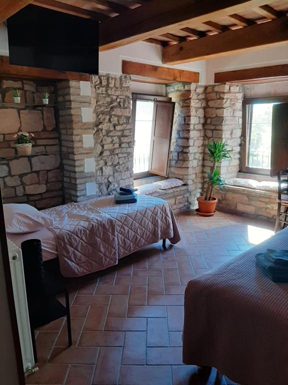 SassoferratoBed & Breakfast Villa Monterosso的一间卧室设有两张床和石墙