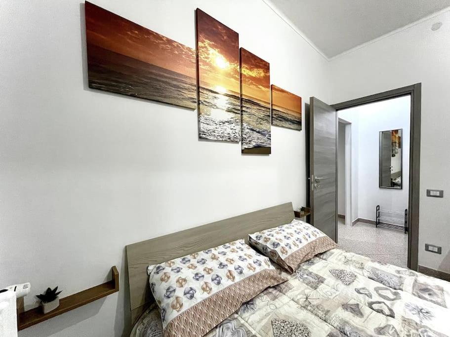 亚历山德里亚Comodo Bilocale in ottima posizione的卧室配有一张壁挂着四幅画作的床
