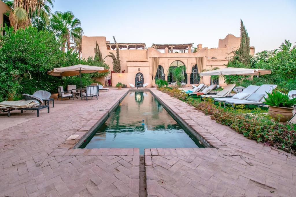 Oulad BarrehilPrestige du Souss的庭院内的游泳池,配有椅子和遮阳伞