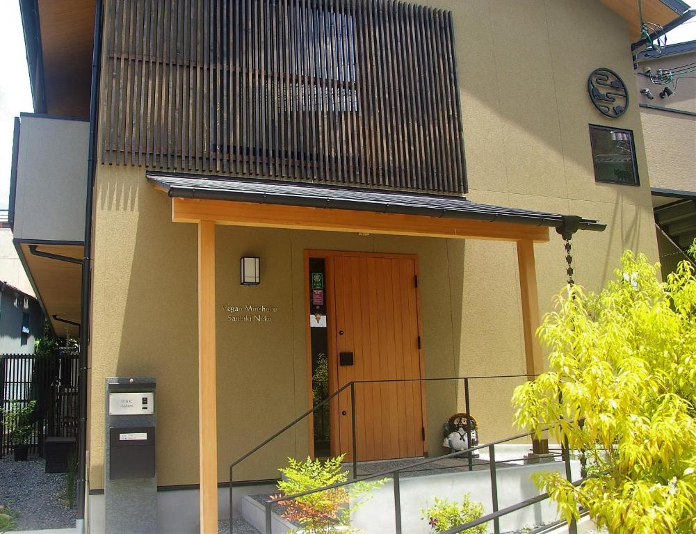 京都Vegan Minshuku Sanbiki Neko的一座带棕色门和阳台的建筑
