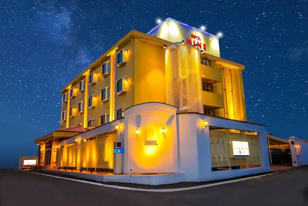 丰田市HOTEL K's MINE的一座黄色的大建筑,晚上有标志