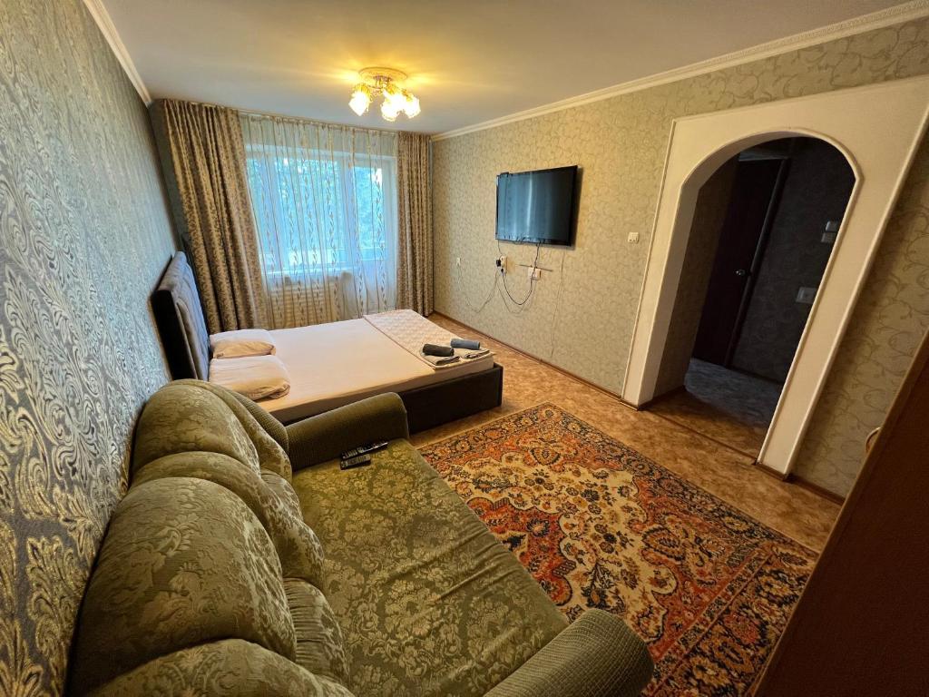 巴甫洛达尔Стандарт Камзина 74 г. Павлодар的酒店客房设有沙发、床和电视。