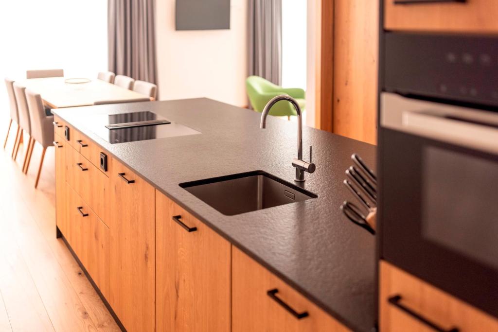 索尔登All-Suite Resort Zwieselstein - Sölden的厨房配有黑色台面和水槽
