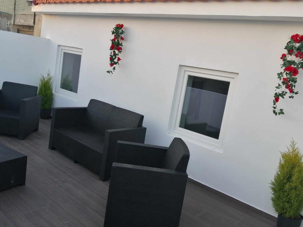 拉夫拉Casa de Praia Daniel的庭院配有黑色椅子,白色墙壁上配有电视。