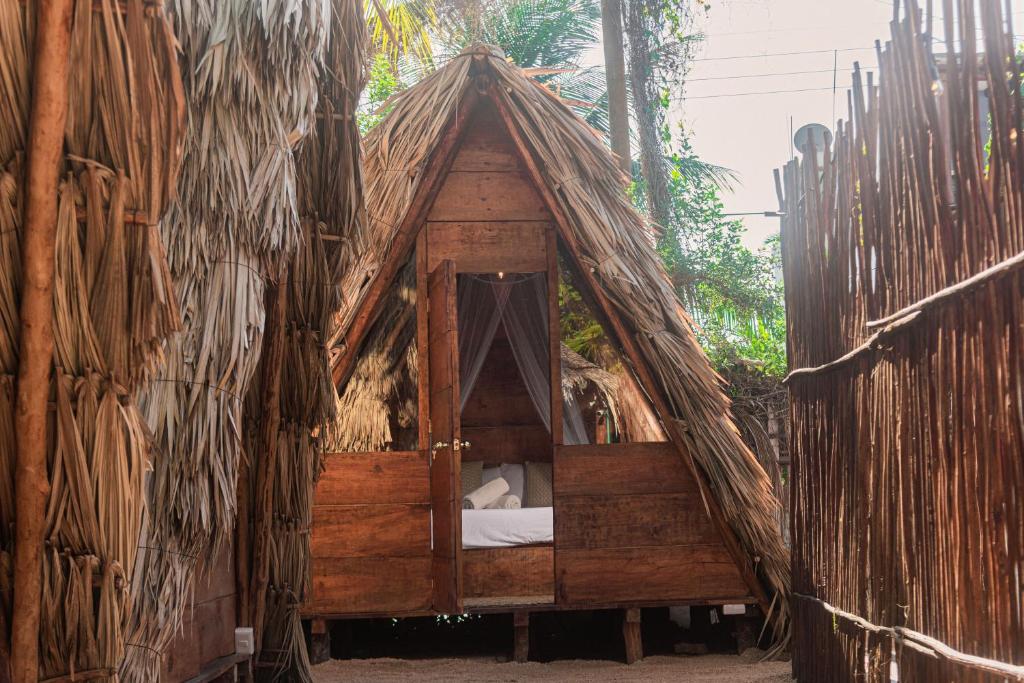 奥尔沃克斯岛Mapache Hostel & Camping的森林茅草帐篷内的一张床位
