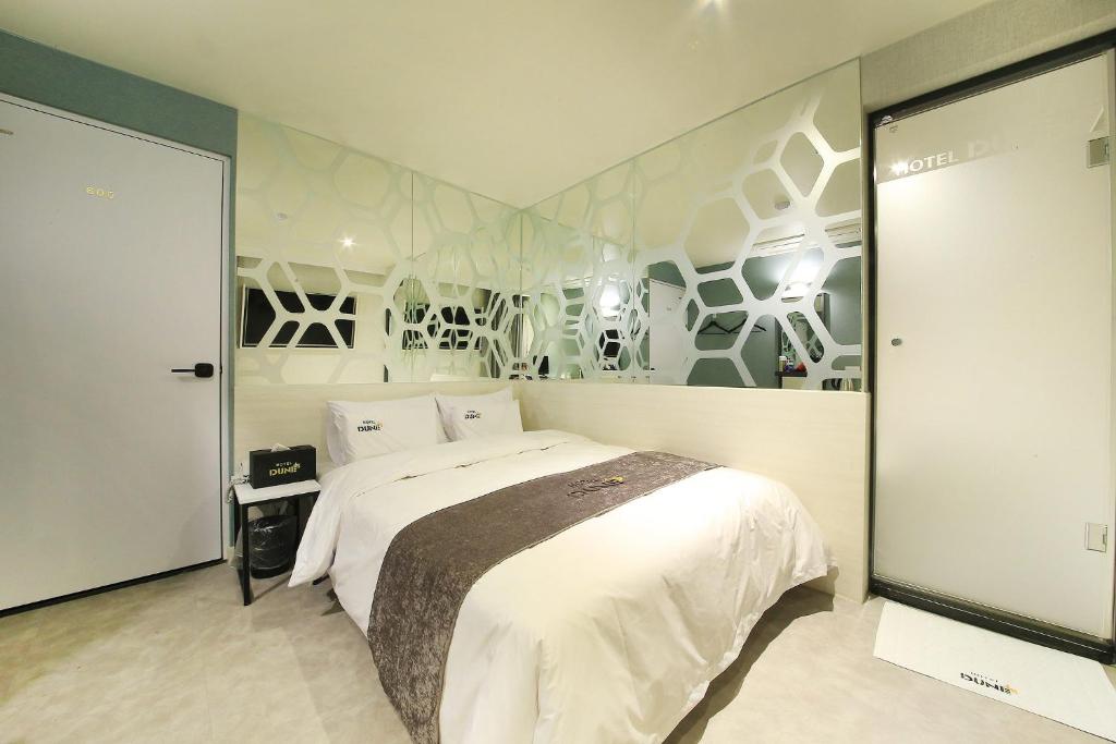 水原市DUNE45的卧室配有白色大床和壁画