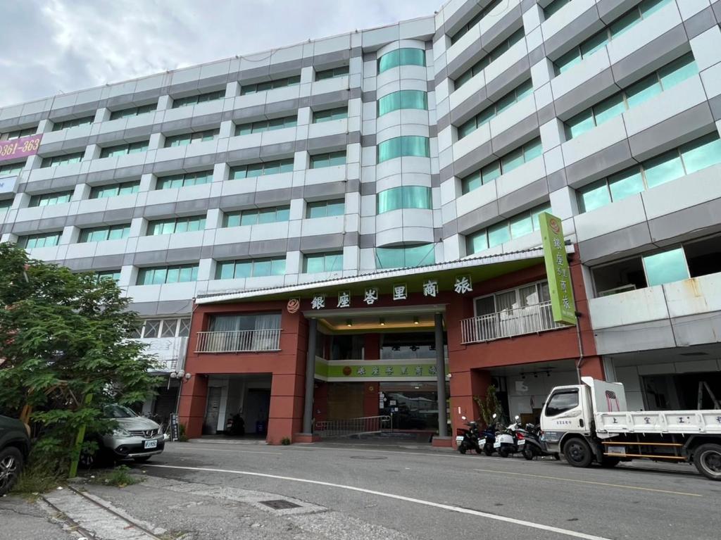 台东台东峇里商旅酒店的一座大型建筑,前面有汽车停放
