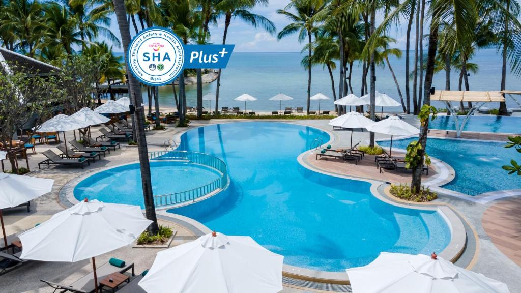 拉迈Outrigger Koh Samui Beach Resort - SHA Extra Plus的度假村的游泳池,配有遮阳伞和海洋