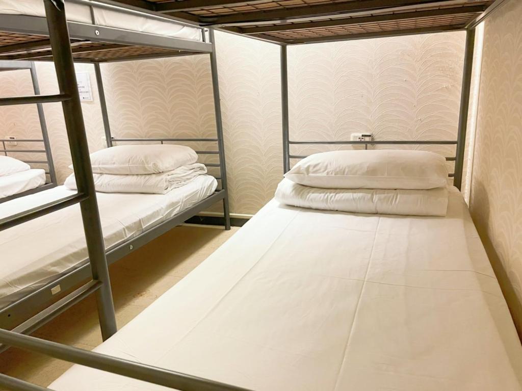 高雄单人房住宿空间 - 高雄林森馆的宿舍间的两张双层床位 - 带白色枕头