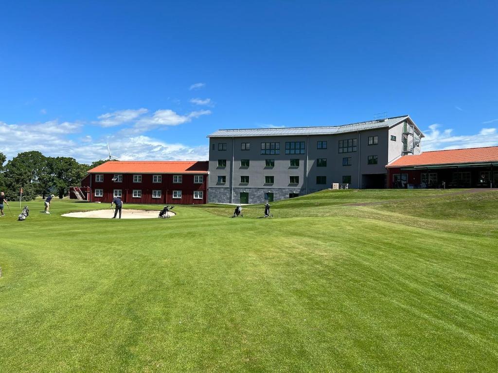 ÖdeshögOmbergs Golf Resort的一群人,在建筑前的田野上