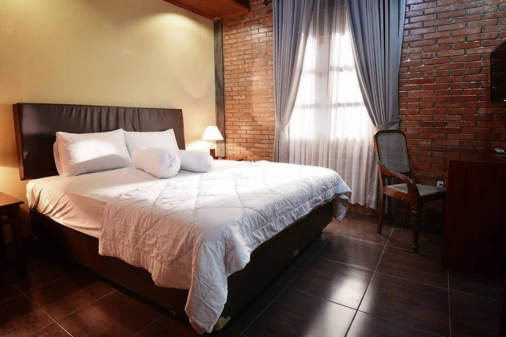 日惹Ndalem Maharani Guest House的一间卧室设有一张床和砖墙