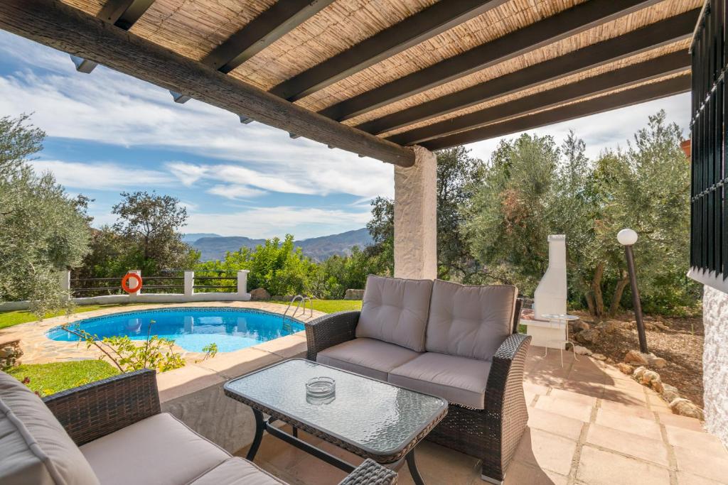 埃尔乔罗El Chorro Villas Casa Rosaleda的一个带沙发和桌子的庭院,毗邻一个游泳池