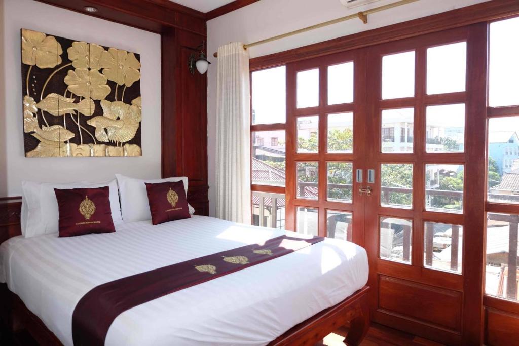 万象曼诺罗姆精品酒店的一间卧室配有一张带白色床单和窗户的床。