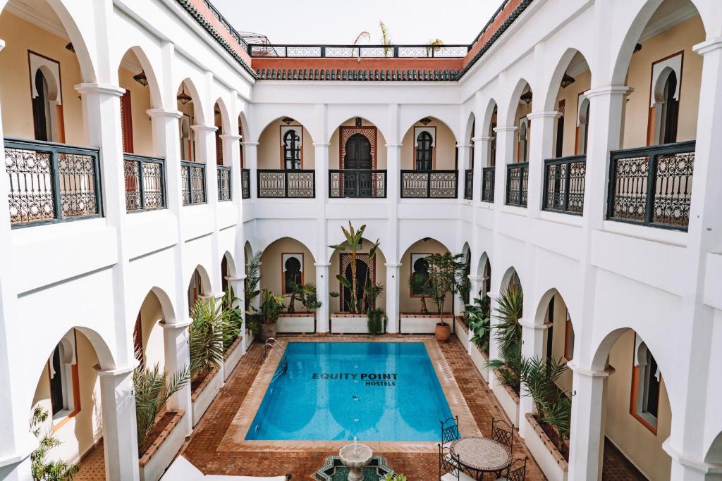 马拉喀什马拉喀什艾奎特酒店的一座带游泳池的室内庭院,位于一座建筑中