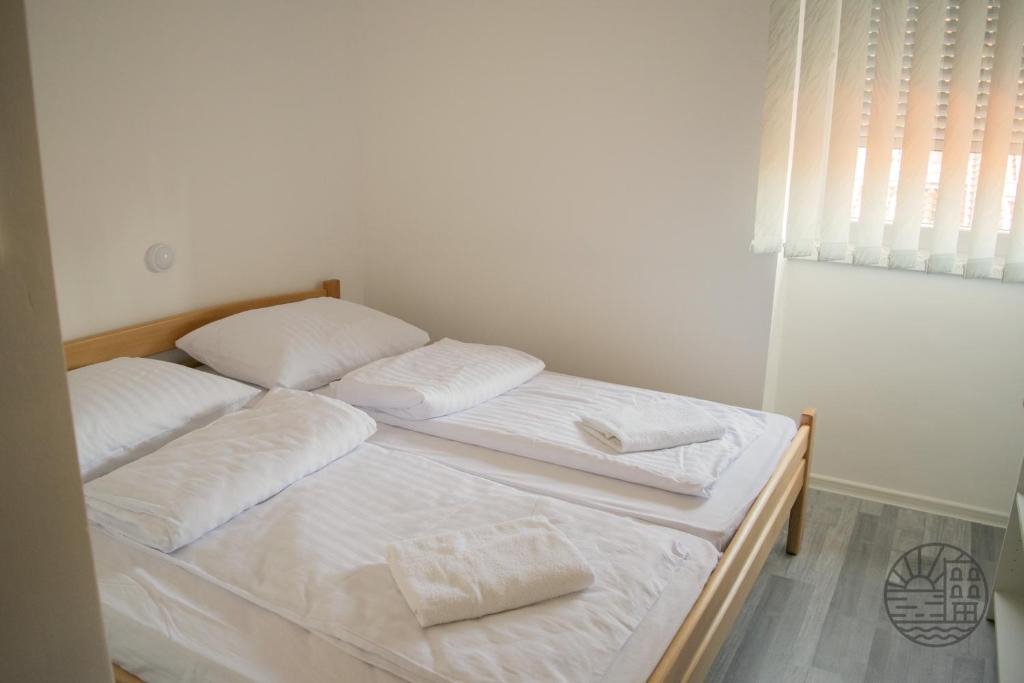 波尔托罗Počitniški dom Portorož / Portoroz Holiday Home的配有2张床的带白色床单和枕头的客房
