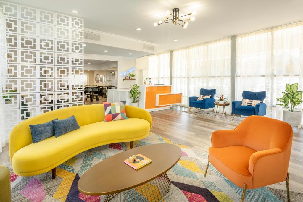 谢尔曼·奥克斯The Sojourn Los Angeles - Sherman Oaks的客厅配有黄色沙发和2把橙色椅子
