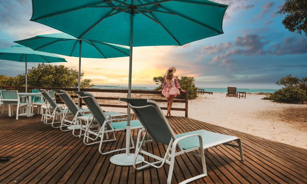 比亚米尔港Isamar Hotel的一位站在海滩上的妇女,她有椅子和遮阳伞