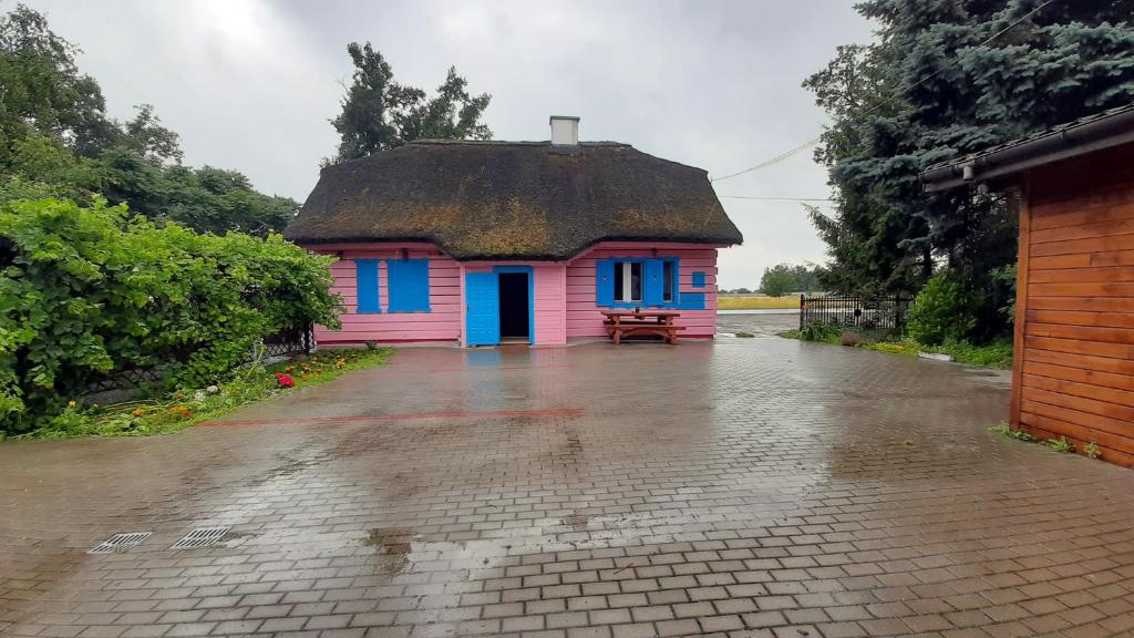KruszynRóżana Karczma的一座粉红色和蓝色的小房子,屋顶