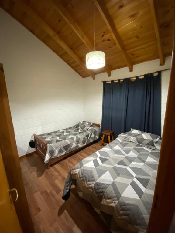 埃斯克尔Cabaña Lucio的配有蓝色窗帘的客房内的两张床